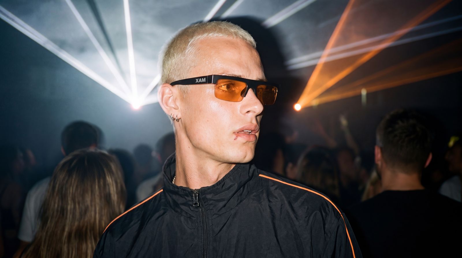 Model wearing XAM sunglasses in a club with laser lights